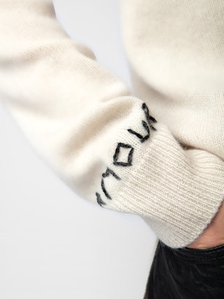 Mirka Cashmere Cardigan - A luxurious blend of softness and Parisian flair. Crafted from 100% premium cashmere, this ecru-hued cardigan offers a cozy yet lightweight feel, perfect for layering across seasons. The design features a contrasting black heart motif on the chest, complemented by intarsia jacquard slogans "Je t'aime" and "Amour" that add a touch of romantic charm.​