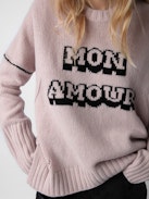 Malta Mon Amour Sweater - Wrap yourself in comfort with the women’s “Mon Amour” sweater, crafted from soft primrose pink merino wool. Featuring an intarsia jacquard “Mon Amour” slogan and delicate pointelle ZV signature, this sweater adds a touch of elegance to your wardrobe. Its thumbholes, ribbed trim, and classic round neckline offer both style and practicality. A cozy yet chic essential, this mon amour sweater is perfect for any occasion.