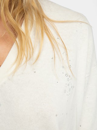 Wully Diamanté Sweater - Cozy meets cool with a touch of sparkle. This ultra-soft white rhinestone sweater wraps you in effortless warmth without losing its edge. Shimmering crystal accents trace the neckline and scatter across the front, delivering refined, rock-chic glamour. A clean V neck and short sleeves let the white rhinestone sweater layer under leather or stand alone over denim, carrying laid-back polish from crisp mornings to late-night sets.