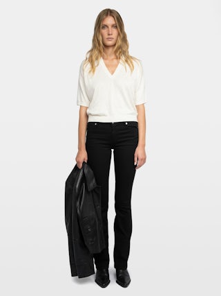 Wully Diamanté Sweater - Cozy meets cool with a touch of sparkle. This ultra-soft white rhinestone sweater wraps you in effortless warmth without losing its edge. Shimmering crystal accents trace the neckline and scatter across the front, delivering refined, rock-chic glamour. A clean V neck and short sleeves let the white rhinestone sweater layer under leather or stand alone over denim, carrying laid-back polish from crisp mornings to late-night sets.