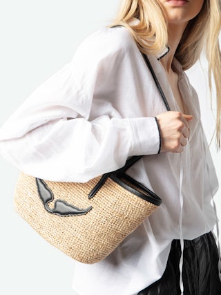 Mini Wings Basket Bag - Small raffia basket with leather handles, adorned with wings.