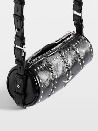 Bolso Le Roudoudou Studs - Bolso de charol de efecto vintage con tachuelas, bandolera ajustable y alas emblemáticas.