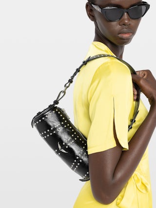 Bolso Le Roudoudou Studs - Bolso de charol de efecto vintage con tachuelas, bandolera ajustable y alas emblemáticas.