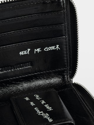 Sunny Purse - Vintage-effect patent leather coin purse with medallion and signature metal wings.