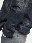 Lederjacke Loumy - Puristische Jacke aus geknittertem Leder mit Reißverschluss, Paspeltaschen und geprägter Flügel-Signatur auf der Rückseite.