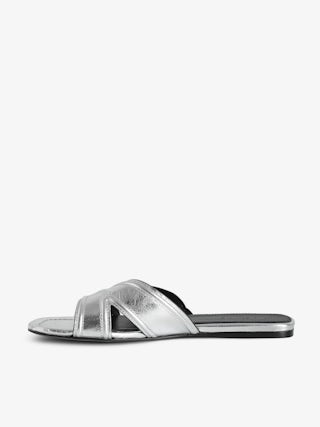 Azora Mules - A harmonious blend of edgy design and luxurious craftsmanship. These mules feature a metallic crinkled leather exterior, exuding a bold yet sophisticated allure. The embossed signature wings add a distinctive touch, embodying the brand's rebellious spirit. Designed with a square toe and crossover strap at the toe, they offer both style and comfort.