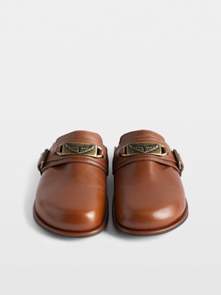 Mules Angie Gourmette - Mules en cuir à bout fermé et semelle confortable, ornée d'une plaque signée et d'une boucle rouleau.