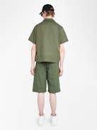 Bermuda Pally - Weite Bermuda-Shorts in Knielänge mit elastischem Bund und Kordelzug, zentraler Knopfleiste und Reißverschluss, begleitet von einer Western-inspirierten Stickerei.