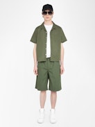 Bermuda Pally - Weite Bermuda-Shorts in Knielänge mit elastischem Bund und Kordelzug, zentraler Knopfleiste und Reißverschluss, begleitet von einer Western-inspirierten Stickerei.