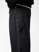 Perry Pants - Black worker-style pants with front patch and rivet details.