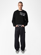 Perry Pants - Black worker-style pants with front patch and rivet details.