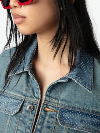 Kioky Denim Jacket - A contemporary twist on a classic wardrobe staple. This fitted denim jacket features a button-up front adorned with subtle rhinestone embellishments, adding a touch of understated glamour to its timeless design. Equipped with multiple pockets, it seamlessly blends functionality with style. Perfect for layering over any ensemble, effortlessly transitioning from casual daywear to chic evening attire.