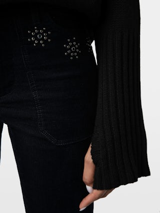 Pantaloni Pista Velluto - Pantalone dritto in velluto a coste con tasche ornate di borchie a fiori e fondo leggermente svasato.