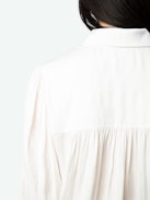 Trenta Satin Blouse - Long-sleeved white satin blouse with buttoned V-neck and gathered shoulders.
