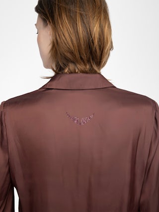Chemise Thely Satin - Chemise en satin, manches longues, fermeture boutonnée et strass aile au dos.