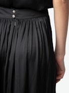 Jady Satin Skirt - Long black satin pleated skirt with slit, zip closure, and jewel button.