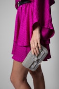 Kate Sparkle Wallet Bag - Shimmer with effortless elegance with the Kate Sparkle Wallet Bag, a dazzling statement piece designed for versatility. Crafted in sparkling silver, this compact yet chic bag features a signature studded metal ring and an engraved flap inspired by Kate Moss. Wear it on your shoulder with the removable chain strap or slip it into a larger bag as a sleek wallet. A must-have sparkle wallet that blends fashion and function seamlessly.
