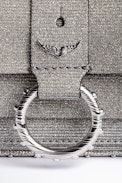 Kate Sparkle Wallet Bag - Shimmer with effortless elegance with the Kate Sparkle Wallet Bag, a dazzling statement piece designed for versatility. Crafted in sparkling silver, this compact yet chic bag features a signature studded metal ring and an engraved flap inspired by Kate Moss. Wear it on your shoulder with the removable chain strap or slip it into a larger bag as a sleek wallet. A must-have sparkle wallet that blends fashion and function seamlessly.