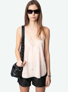 Christy Heart Camisole - A delicate blend of romance and modern style. This lingerie-inspired pink silk camisole features the exclusive Flash Hearts print, adding a playful touch to its elegant design. Crafted from luxurious silk, it offers a soft and comfortable feel against the skin. The V-neckline is adorned with contrasting lace trim, enhancing its feminine appeal, while the thin, adjustable spaghetti straps ensure a personalized fit. Its versatile style makes it a perfect addition to any wardrobe, suitable for both casual layering and sophisticated ensembles.